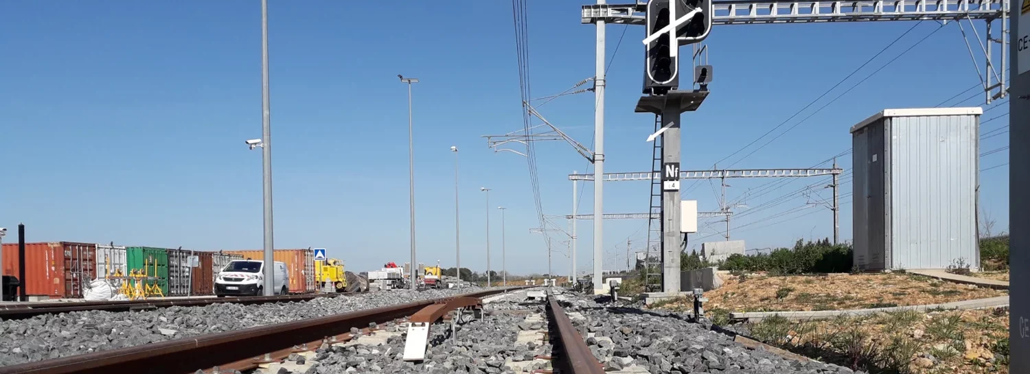 Photo qui d'une voie ferrée avec un feu de signalisation électrique.