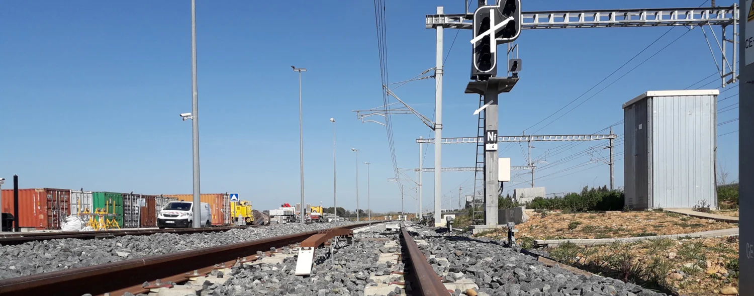 Photo qui d'une voie ferrée avec un feu de signalisation électrique.